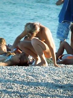 Группа голых нудистов загорают на пляже