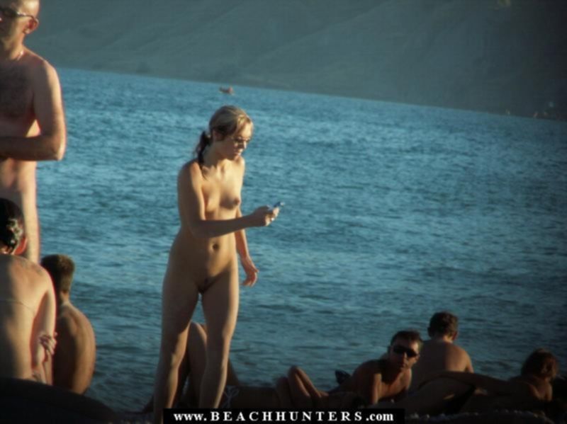 Группа голых нудистов загорают на пляже